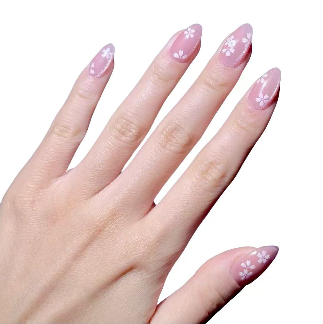 A hand with nails adorned with pink false nails featuring white floral designs.